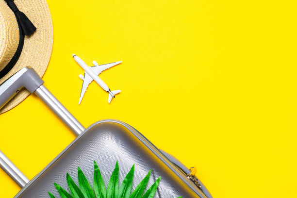 你好,夏天。女性配饰旅行者:行李箱，白色飞机，黄色背景的太阳镜，空白的文字。宁静的海滩场景与复制空间。图片下载