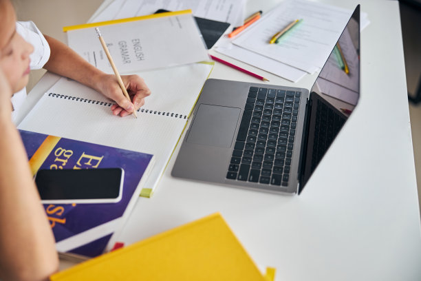 在笔记本对面一个干净的笔记本上写字的人图片下载