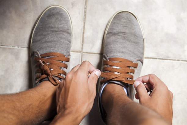 一个年轻的巴西男人正在系网球鞋图片下载