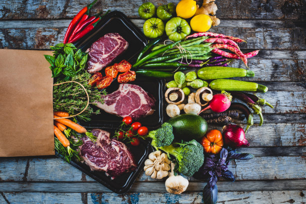 质朴的餐桌上放着真空包装的生牛肉和蔬菜。图片下载