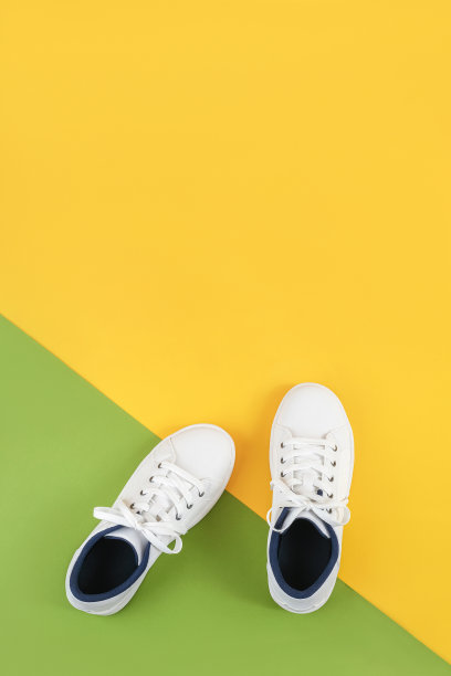 白色的运动鞋，鞋带在绿色和黄色的背景。运动生活方式概念俯视图平坦lay图片下载