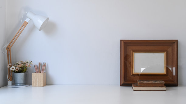 复古的工作空间，框架，铅笔，盆栽植物，咖啡杯，台灯和旧书在白色的桌子上。图片下载