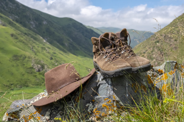 棕色毡帽和磨砂徒步靴在山的背景。图片下载