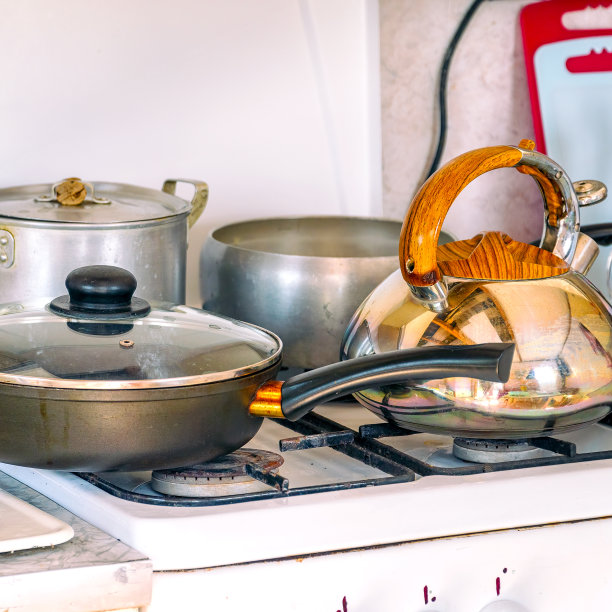 平底锅，煎锅和煤气炉上的水壶。厨房里的盘子图片下载