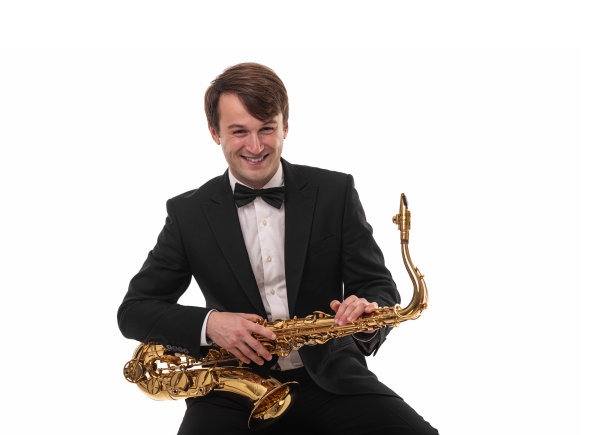 萨克斯管手拿着萨克斯管站在白布上。图片下载