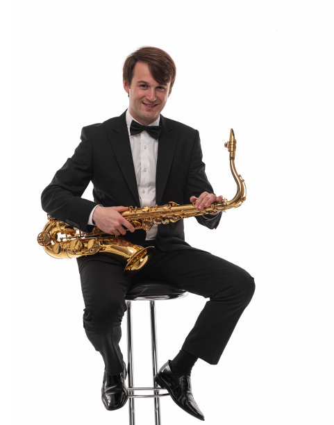 萨克斯管手拿着萨克斯管站在白布上。图片下载