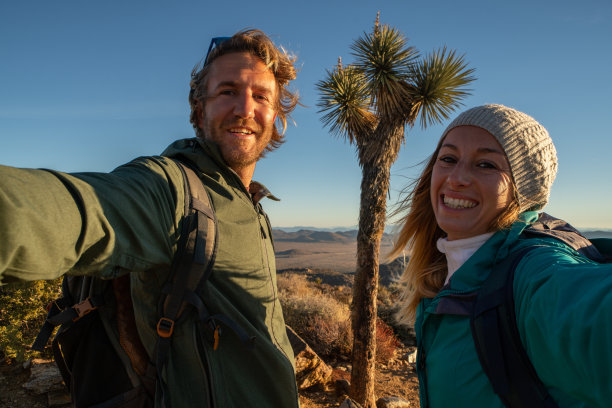 日出时，徒步旅行者在山顶自拍图片下载