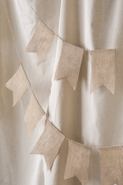 一个装饰旗帜花环的特写，以装饰在米色背景上的照片区。生日庆典的节日背景装饰。有选择性的重点图片下载