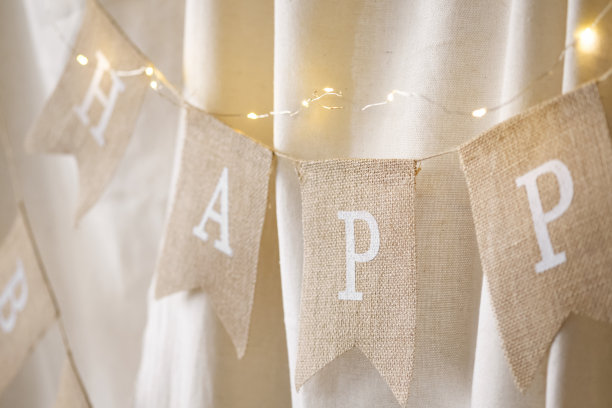 一个装饰旗花环的特写与题词生日快乐装饰在米色背景上的照片区。生日庆典的节日背景装饰。有选择性的重点图片下载