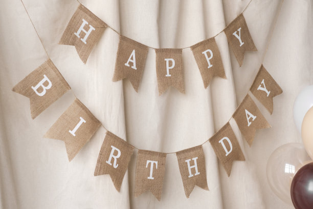 一个装饰旗花环的特写与题词生日快乐装饰在米色背景上的照片区。生日庆典的节日背景装饰。有选择性的重点图片下载