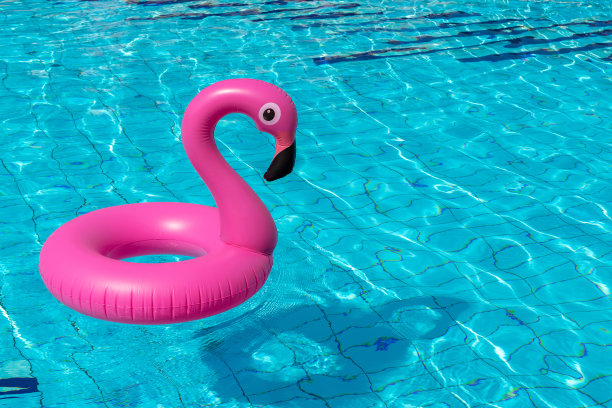 夏天概念背景。粉红色的充气火烈鸟在游泳池的水为夏天的海滩背景。池浮动。图片下载