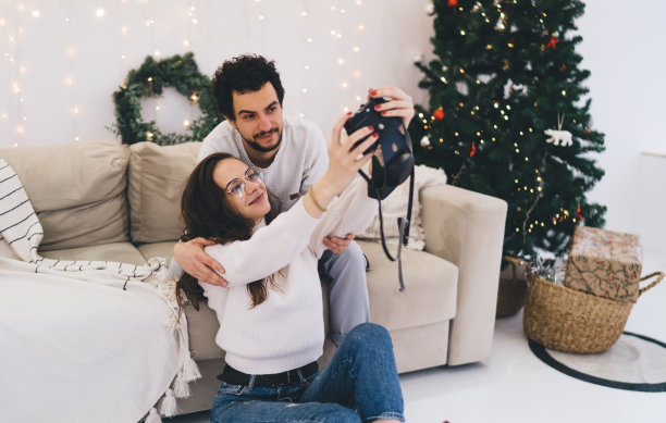 微笑着的白人女友和男友在寒假庆祝新年摆姿势拍照，浪漫的情侣在平安夜在家用相机拍共同的照片图片下载
