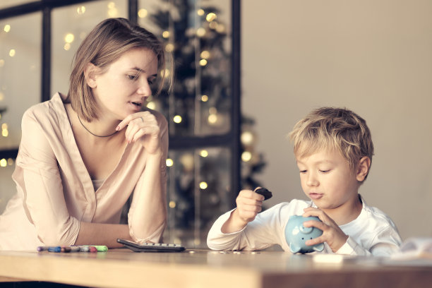 妈妈和孩子把硬币放进存钱罐。对儿童进行财务素养教育。钱,现金、投资图片下载