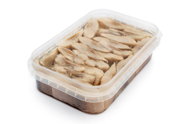 开过的塑料容器里放着油浸过盐的鲱鱼。孤立在白色的。图片下载