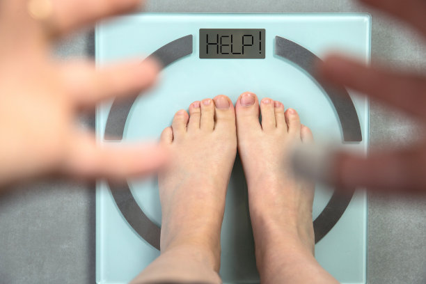 人脚在数字体重秤上，有“帮助”字样，忧虑的手显示，俯视图饮食和健康概念图片下载