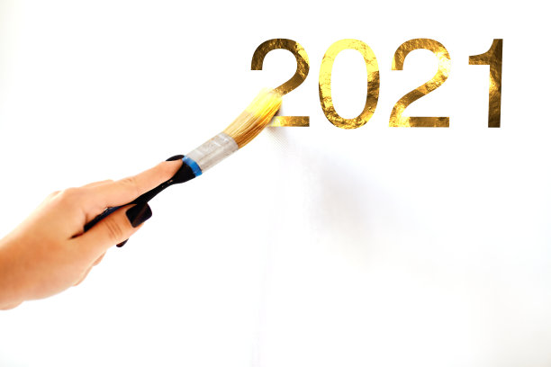一个女人的手用画笔绘制的黄金数字2021的特写图片下载