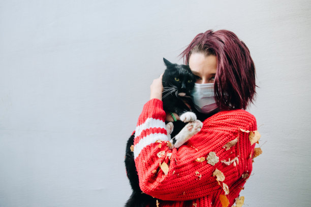 年轻女子抱着一只猫在她的房子外面库存照片图片下载