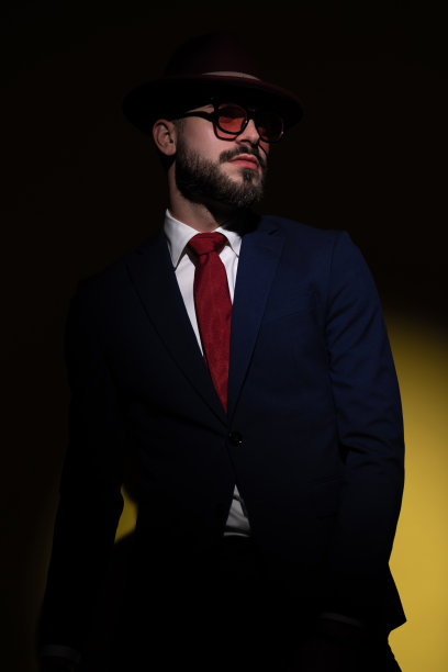 穿着西装、头戴帽子、向一边看的不刮胡子的酷男图片下载