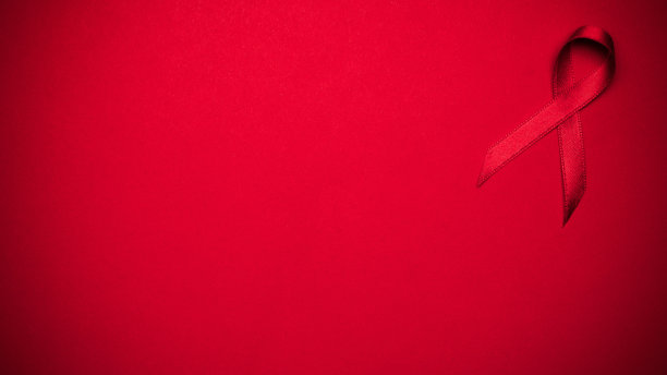 乳腺癌的女人。红丝带标志为世界艾滋病日，背景为深红色。意识有助于预防癌症。医疗保健和医疗理念。图片下载