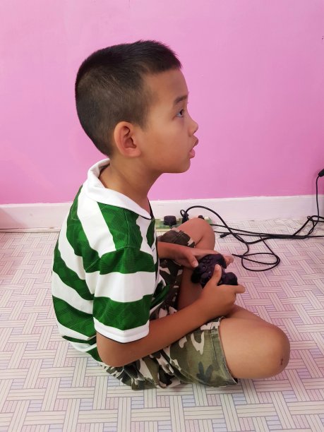 那男孩放学回家后全神贯注地玩电脑游戏。图片下载