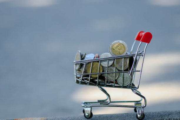 网上购物车满是钱在白色的背景，省钱的概念。带有硬币的红色购物车或手推车。(泰国的钱)。图片下载