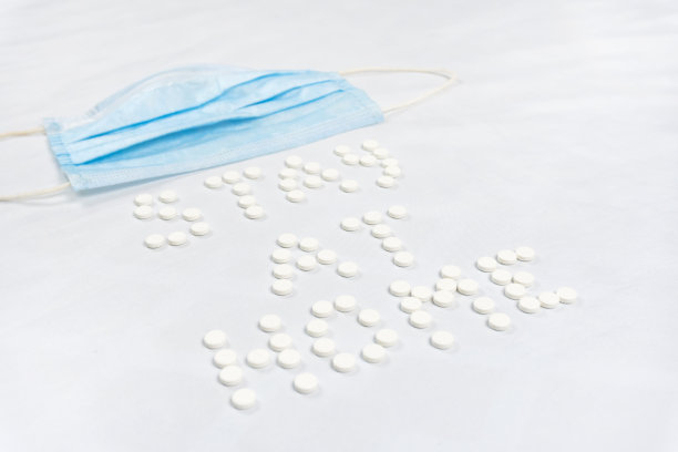 留在家里的字母由圆形的白色药丸。白色背景图片下载