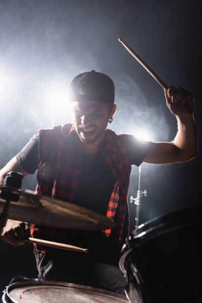 摇滚乐队鼓手拿着鼓槌和打鼓与背光和烟雾的背景图片下载