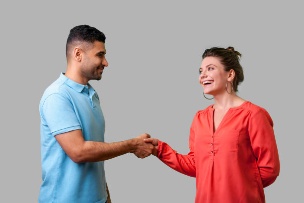 很高兴认识你！一对年轻夫妇握手的休闲装肖像，灰色背景隔离图片下载