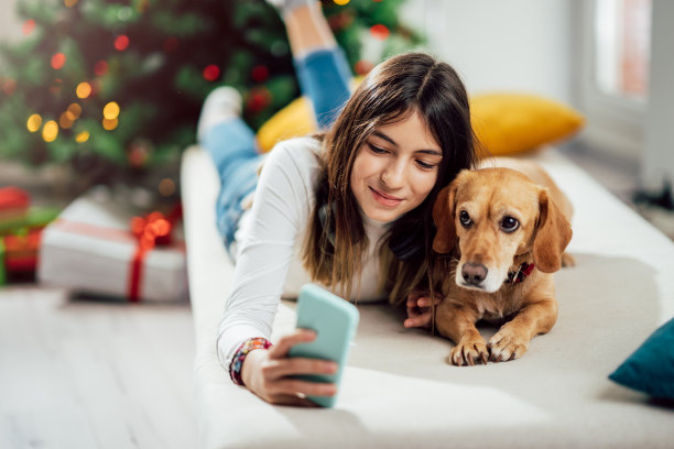 少女和她的狗在圣诞树前自拍图片下载