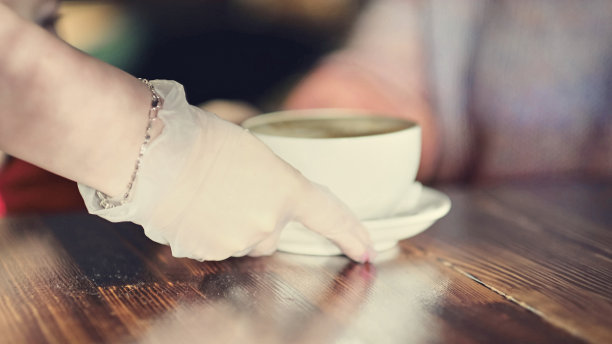 戴手套的服务员在咖啡馆工作，端着咖啡图片下载