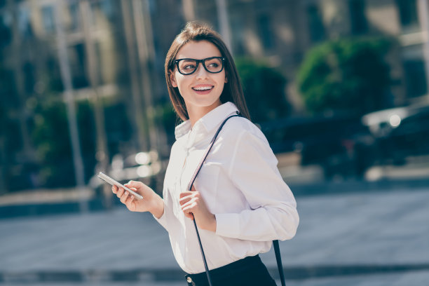 迷人的年轻女士穿着白色正装衬衫眼镜手提袋拿着现代设备的照片图片下载