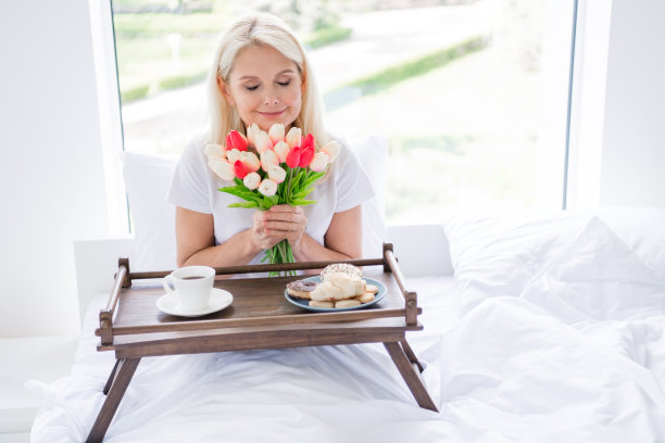 照片迷人的老夫人亚麻闭上眼睛，抱着郁金香，喜上眉梢，早餐床上托盘食物饼干室内图片下载