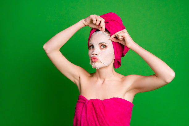 女士在淋浴时使用胶原蛋白棉面膜程序梳理，穿毛巾身体头部隔离绿色背景图片下载