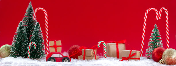 节日构图圣诞红车与礼盒在松林里许多不同的礼物在红色的背景。新年贺卡的概念图片下载