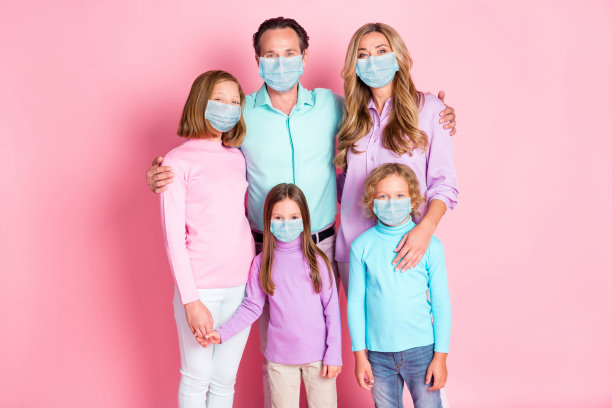 照片全是大田园诗和谐的家庭，妈妈爸爸三个孩子拥抱，手牵手，戴口罩，休闲风格的衣服孤立的粉红色背景图片下载