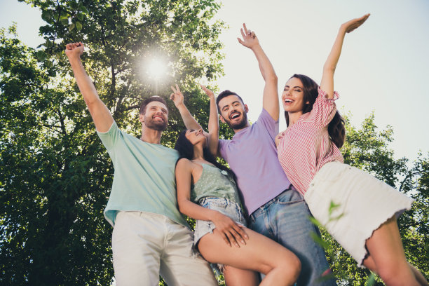 低角度的照片，快乐的年轻褐发男女举起手握拳，幸运的周末在户外图片下载