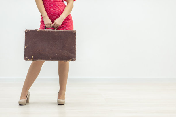 裁剪镜头的女性在红色裙子拿着一个皮革公文包在排队孤立的白色背景。图片下载