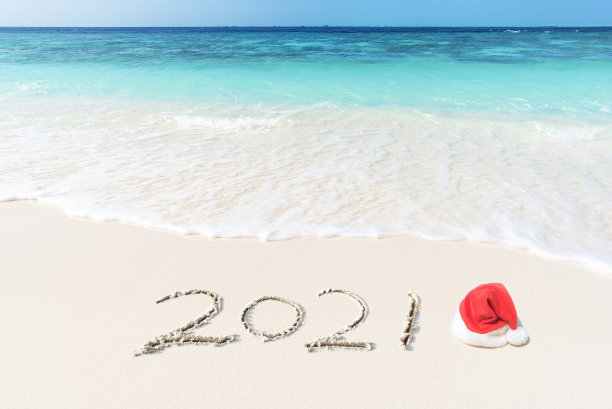 用圣诞帽写在热带沙滩上的2021图片下载
