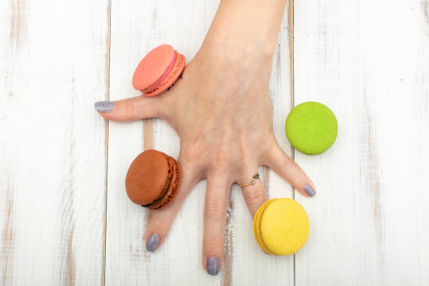 通心粉蛋糕在一个女人的手在一个白色的木制背景。图片下载