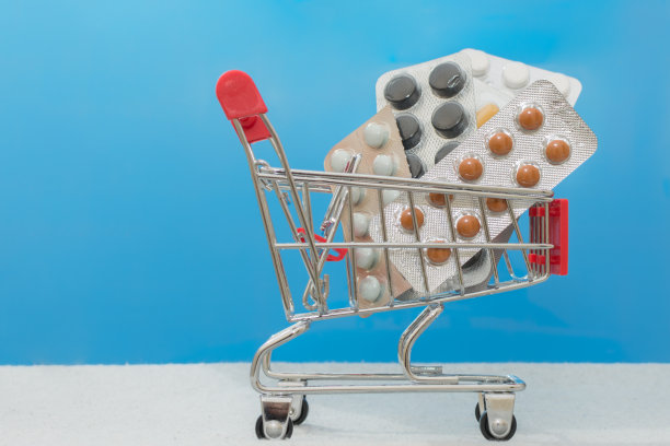 超市手推车与各种各样的药片在泡罩包装在一个蓝色的背景。防止冠状病毒。一个网上药房的想法，网上药品销售，横向图片。图片下载