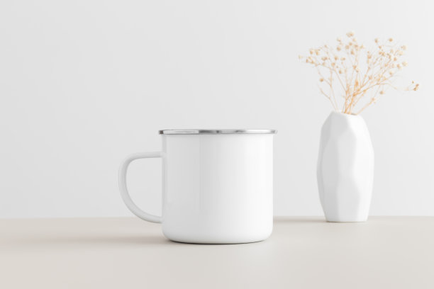 搪瓷杯子模型与一个吉普赛菲拉花瓶在米色的桌子上。图片下载