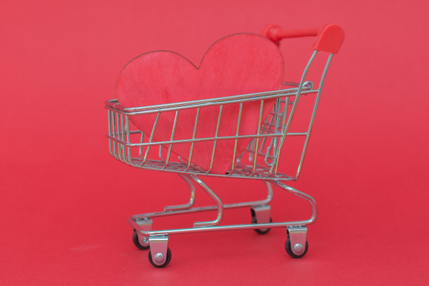 一个超市小推车的特写，红色的背景上有一颗红心。水平的照片图片下载
