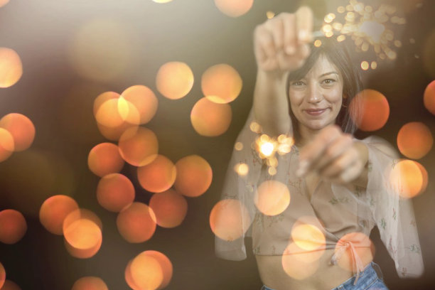 特写照片的愉快的白人女孩拿着孟加拉灯。快乐的年轻女子的肖像在红色睡衣孤立的黑色背景与火花图片下载