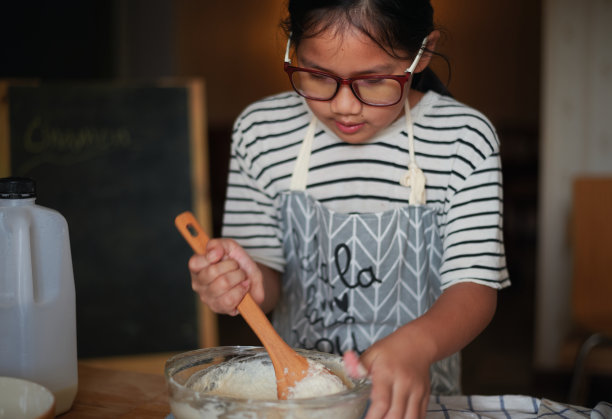 一个女孩在玻璃碗里拌面团图片下载