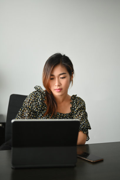 一个年轻的女商人坐在工作空间里用平板电脑工作。图片下载