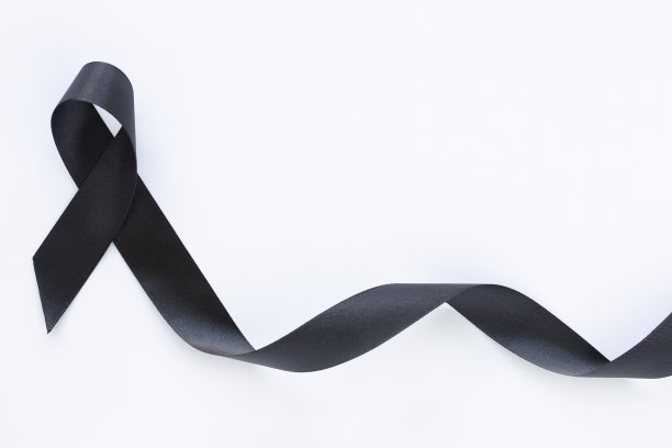 黑色丝带卷曲在白色织物背景与复制空间，象征皮肤癌意识月，黑色素瘤癌症，悼念丝带象征。医疗保健和保险概念。图片下载
