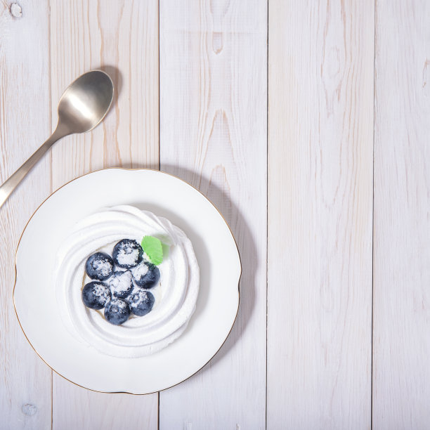 顶视图上的健康素食甜点安娜巴芙洛娃在白色木桌和咖啡勺。图片下载