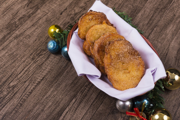 Rabanada。篮子里的法式吐司配上圣诞装饰品。圣诞节和年终甜点。铃铛、球和圣诞装饰品。特写照片，左边有文字空间。图片下载