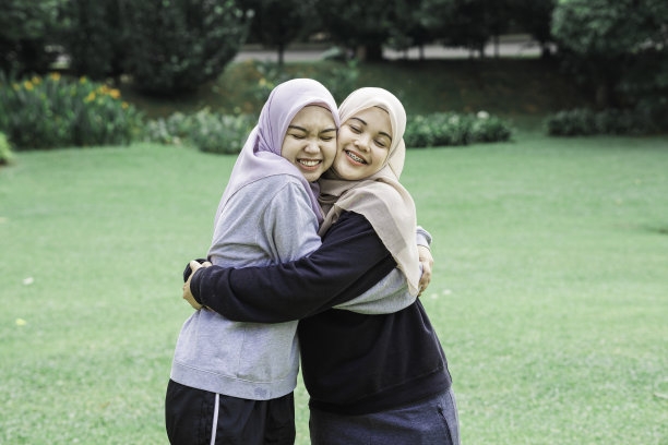 在一个阳光明媚的日子里，漂亮的穆斯林青少年在做完一些运动后坐在一个公园里图片下载