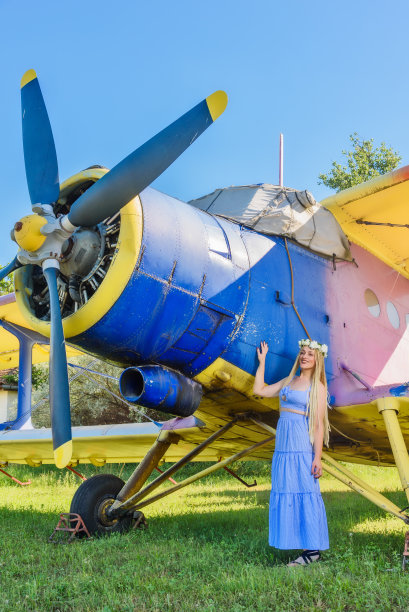 一个可爱的女人站在一架废弃的飞机旁。戴花环的妇女头上戴着花环的妇女图片下载